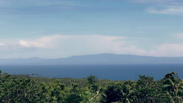 Wide view of Siquijor Island framed by lush swaying foliage. Popular summer travel holiday destination in the Philippines