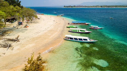 Wooden tourist boats moored off the beach and coral reef of a small tropical island (Gili Air, Indonesia)