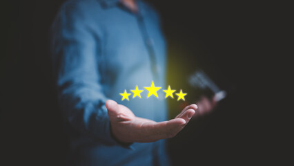 A man hand holding up five stars in his hand for best satisfaction and quality feedback review....