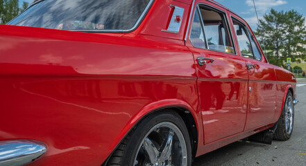 A close-up view of a red vintage car from the side.