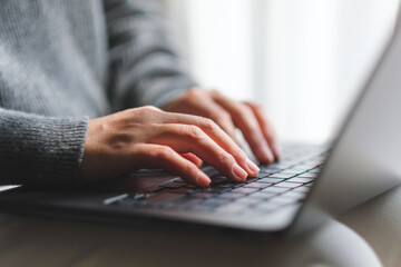 Closeup image of a woman typing on laptop computer at home