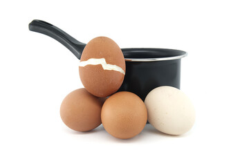 Cooking pot surrounding eggs, one cracked during boiling