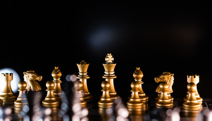 Golden chess pieces in dramatic backlighting