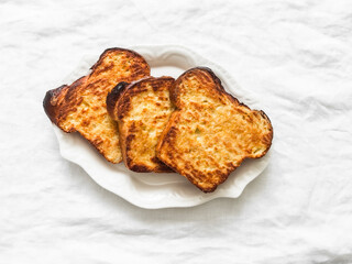 Slice of crispy baked homemade brioche french toast on a light background, top view