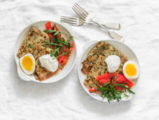 Delicious  breakfast , brunch - potato dill crepes, boiled egg, lightly salted salmon, arugula on a light background, top view