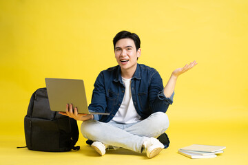 Portrait of Asian male student posing on yellow background