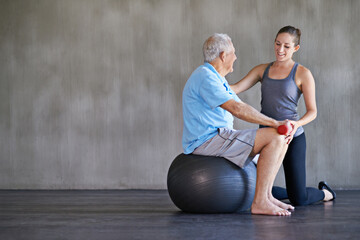 Physiotherapist, dumbbells and happy elderly man on ball for fitness or rehabilitation at gym on...