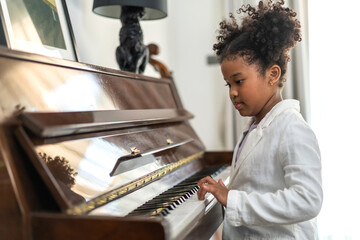 African young child creativity and learning playing piano, talented pianist engrossed in music,...