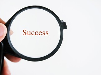 Hand holding magnifying glass focus on the text written SUCCESS. Concept of focusing on what matter...
