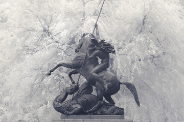Statue of George and the Dragon, man on horseback spearing a beast in black and white with...