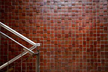 赤茶色のタイルの壁と階段の手すり