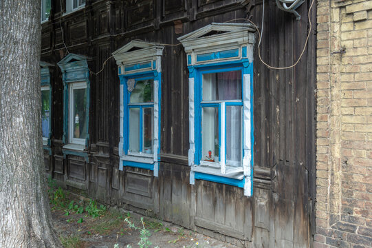 An old wooden house built in the 19th century. The architecture of the last century. A dilapidated residential house built in the last century. An old house with carved wooden elements on the windows.