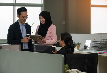 Group of Asian business people working together in open office on new project. Male and female office employee looking at digital tablet PC while standing in open space office - 767610816