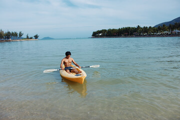 Happy Asian Man Enjoying Kayaking Adventure in Tropical Paradise