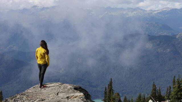Person looking at mountain view. Hiker walking on summit of Blackcomb mountain top in Whistler. Tourist hiking in summer enjoying view of mountain landscape in British Columbia, Canada