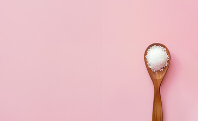 cristaux de sel blanc de Camargue, France  dans une cuillère en bois, sel de mer ou sel de roche sur fond rose pastel avec espace négatif copy space