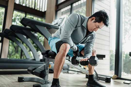 A man doing exercises biceps with dumbbell  in gym. Fitness, workout and traning concept.
