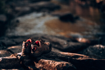 Hiking shoes and trekking pole on the rocks by the stream from the waterfall.