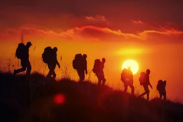 Zelfklevend Fotobehang A group of people walks through the mountains at sunset © sonatik