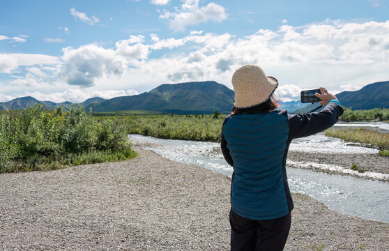Woman taking photos of the mountains using a smartphone. Denali National Park and Preserve. Alaska. USA.