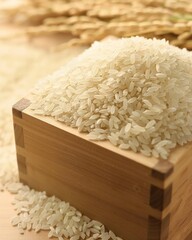 A wooden box with rice in it sits next to a pile of rice