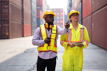 Portrait Asia logistic engineer man worker or foreman use walkie talkie working with African American foreman finger point with container background	 - 767647219
