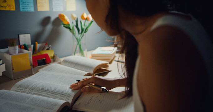 Young Asia Teen Girl Student Distance Learning Lesson And Doing Homework Sitting At Desk In Living Room At House Night. Work From Home, Social Distancing, Quarantine For Corona Virus Prevention.