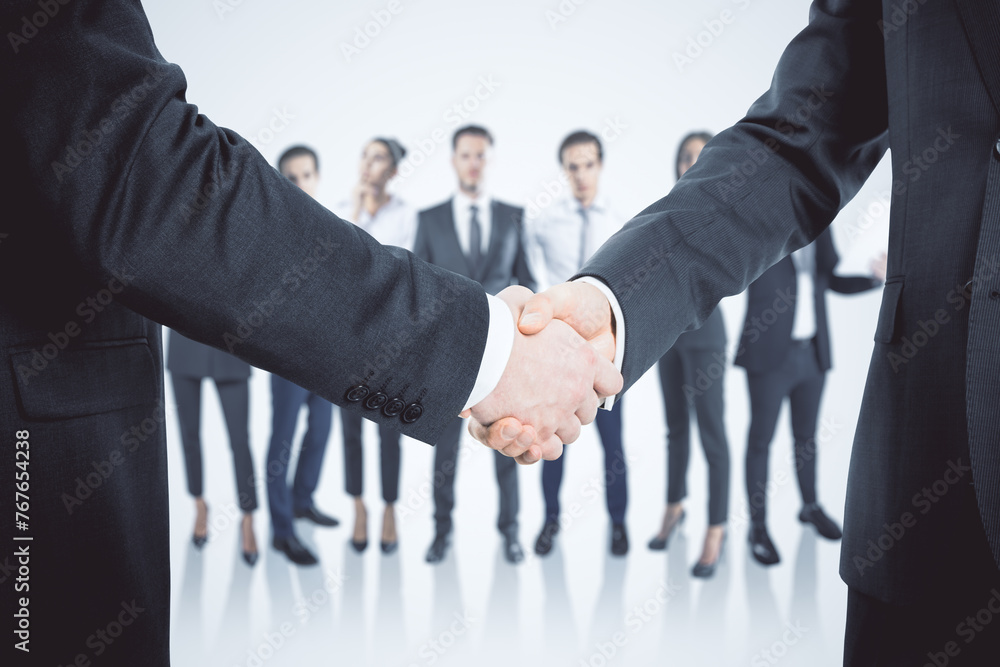 Poster close up of two males shaking hands with their diverse blurry colleagues in the background. concept 
