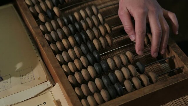 Vintage tone of Man's hands accounting with old abacus and writes anything in the copy book. picture financial concept design.
close-up plan