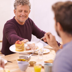 Breakfast, mature and man with food on dining table for eating with smile for healthy meal and diet. Adult, male person and father to son with visit for Easter holiday in home for communication