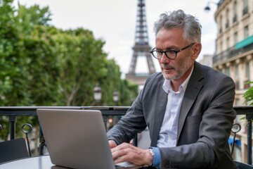 Mature businessman using laptop in Paris, France. Eiffel tower in the background
 - obrazy, fototapety, plakaty