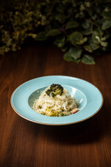 vegetarian pasta pesto served in blue dish in restaurant on dark background