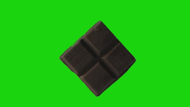 Piece of chocolate candy bar on chromakey green screen background. Sweet morsel on edge rotating. Detailed view of chocolate video element.