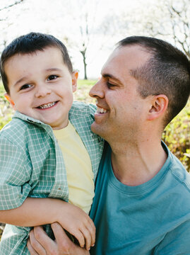 Dad and son laugh and smile together in sunshine