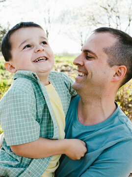 Laughing and smiling father holding son together in spring