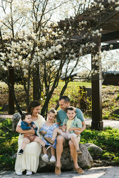 Family laughing together under spring bloom tree in garden