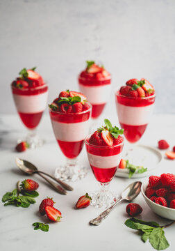 Layered berry, jelly and mousse parfait desserts on white background.