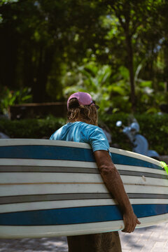 Man surfer with long bleached hair with a surfboard.