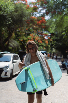 Man surfer with long bleached hair with a surfboard.
