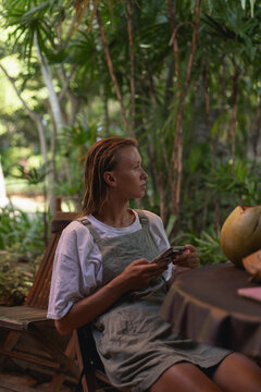 A woman drinks a fresh coconut on a tropical island.