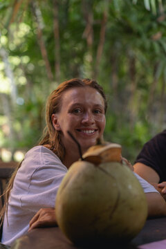 A woman drinks a fresh coconut on a tropical island.