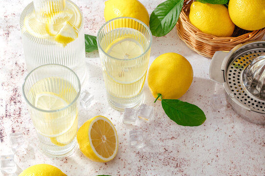 summer lemon lemonade in a glass and decanter. Lemons are scatte