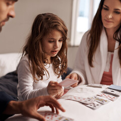 Parents, girl and fun of playing cards in home for bonding, learning and relax with strategy in...