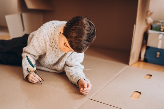 Teenage boy cuts out cardboard with scissors