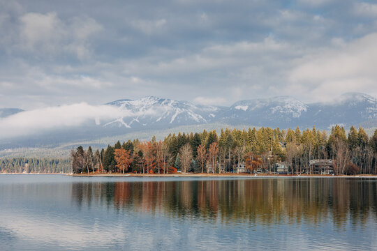 Whitefish lake in winter with trees and houses reflected in water