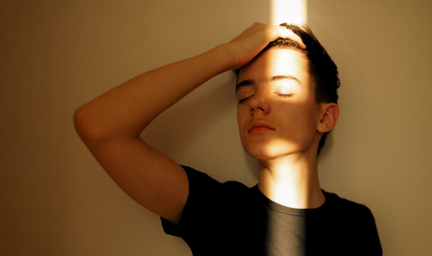 Emotional portrait of a teenager in a ray of sunshine