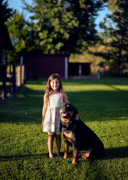 Portrait of smiling girl standing with Rottweiler on grass in garden