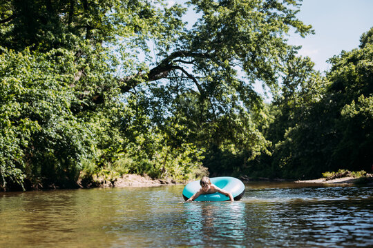 Child floating down river in inflatable innertube on summer day