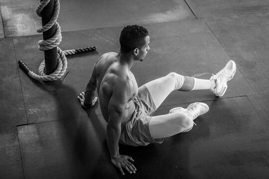 Fit Shirtless Man Sitting on Gym Floor Next to Ropes