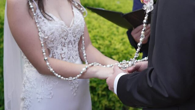 A bride and groom holding hands while getting married in an outdoor religious ceremony